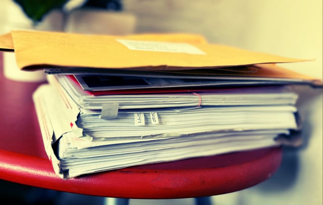 A stack of paper on a red stool.