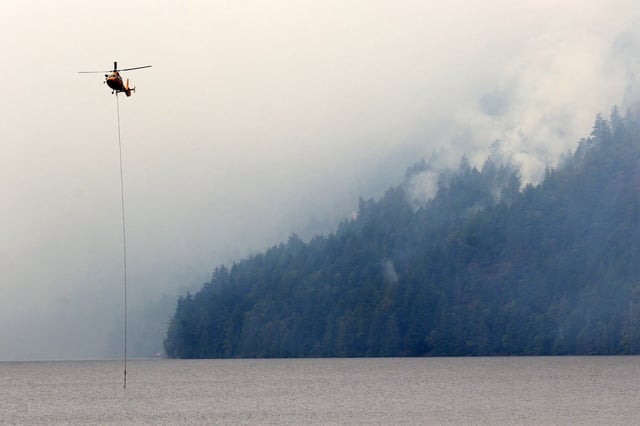 A helicopter refills a bucket of water at Cameron Lake off Highway 4 where the Wesley Ridge wildfire continues to burn out-of-control near Coombs, B.C., on Sunday, August 3, 2025. THE CANADIAN PRESS/Chad Hipolito