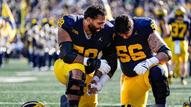 Michigan offensive lineman Giovanni El-Hadi (58), left, and offensive lineman Dominick Giudice (56) pray together before kickoff against Oregon at Michigan Stadium in Ann Arbor on Saturday, Nov. 2, 2024.
