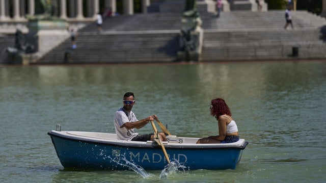 Ein Mann rudert bei heißem Wetter ein Boot im Retiro-Park