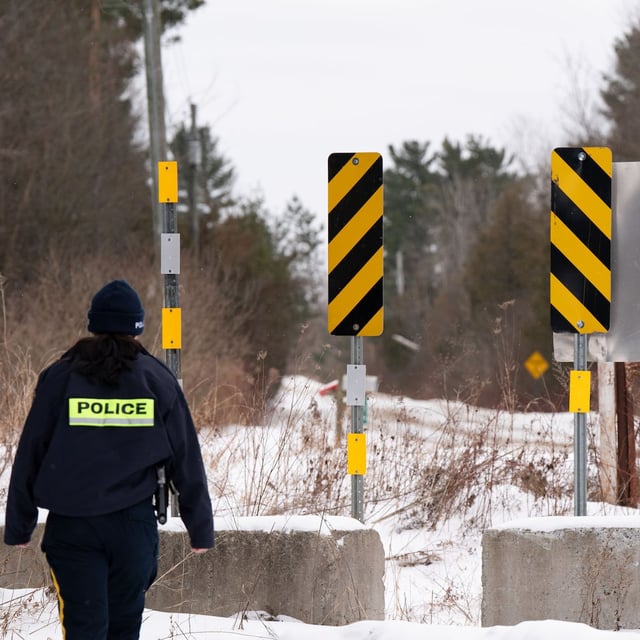 A RCMP officer checks  the border between Quebec and New York State on Roxham Road in St. Bernard-de-Lacolle, Que. on Wednesday, Jan.15, 2025. THE CANADIAN PRESS/Christinne Muschi