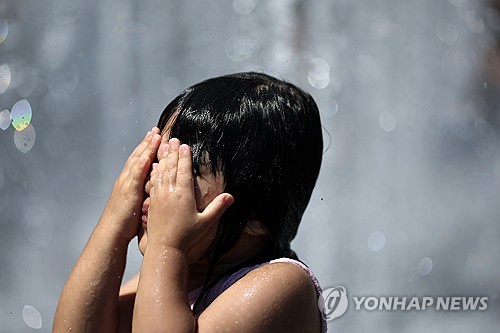 A child plays in the water in Gwanghwamun Square in central Seoul on July 27, 2025. (Yonhap)