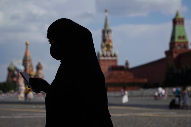 A woman wearing a niqab, checks her phone while walking along the Red Square in Moscow, Russia, Wednesday, July 30, 2025. (AP Photo/Pavel Bednyakov)