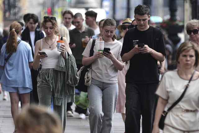 Pedestrians look at their phones while walking through St. Petersburg, Russia, on Monday, July 14, 2025. (AP Photo/Dmitri Lovetsky)