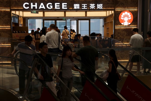 People ride escalators near a store of Chinese tea chain Chagee, at a shopping mall in Beijing, China July 31, 2025. REUTERS/Florence Lo/FIl  photo