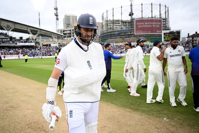 Chris Woakes of England walks off the field at the end of the match after batting with his arm in a sling on day five.