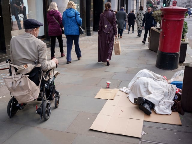 A man drives a powered wheelchair past a rough sleeper on Regent Street, on 5th February 2025, in London, England. (Photo by Richard Baker / In Pictures via Getty Images)