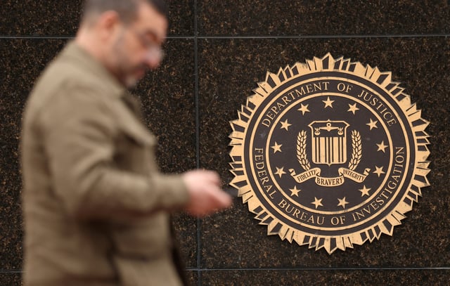 A person passes by the FBI seal on the wall of the FBI headquarters, in Washington, U.S., February 3, 2025. REUTERS/Kevin Lamarque/File Photo