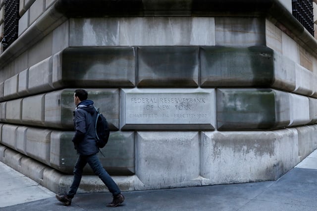 A man passes by the cornerstone on the Federal Reserve Bank of New York in the financial district in New York City, U.S., March 4, 2019. REUTERS/Brendan McDermid/File Photo