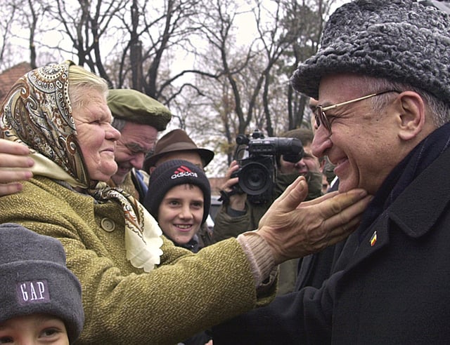 FILE - An elderly Romanian woman reaches out to President Ion Iliescu, right, at the end of celebrations for Romania's national day in Bucharest on Saturday, Dec. 1 2001. (AP Photo/Vadim Ghirda, File)