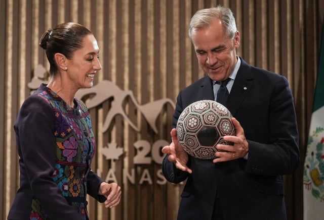 Canadian Prime Minister Mark Carney, right, spins a soccer ball with beaded Huichol art on it after being gifted it by Mexican President Claudia Sheinbaum, before a meeting at the G7 Summit in Kananaskis, Alta., on Tuesday, June 17, 2025. THE CANADIAN PRESS/Darryl Dyck
