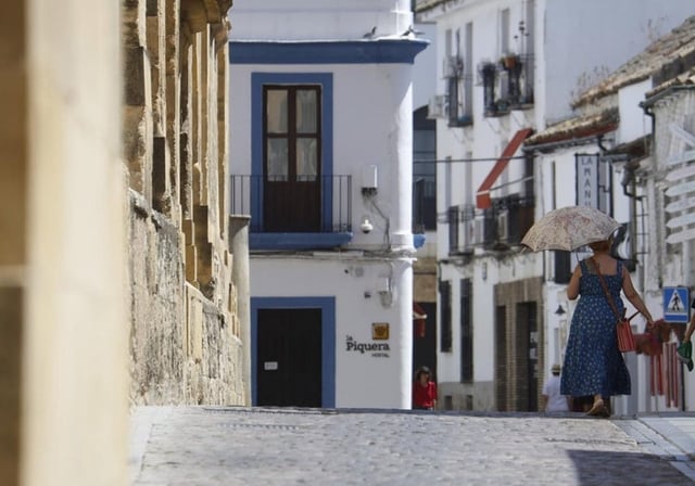 Una mujer se protege del sol con un paraguas por las calles de Córdoba