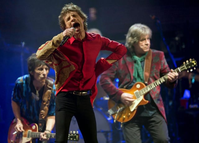 ARCHIVO - Mick Jagger, en el centro, Ronnie Wood, a la izquierda, y Mick Taylor, de la banda de rock británica The Rolling Stones, actúan en el escenario principal de la Pirámide en Glastonbury, Inglaterra, el 29 de junio de 2013. (Joel Ryan/Invision/AP, archivo)