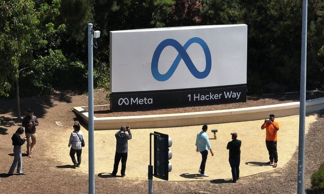 FILE: People gather in front of a sign posted at Meta’s headquarters in Menlo Park, Calif., on July 7, 2023. 