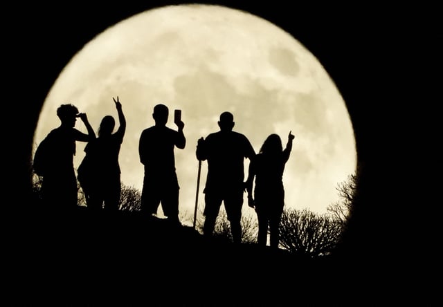 People stand with the full "sturgeon moon" in the background, in Arguineguin, on the island of Gran Canaria, Spain, August 1, 2023.