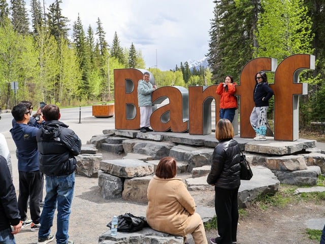Visitors pose for photos with the entrance sign to Banff on Thursday May 22, 2025. 
