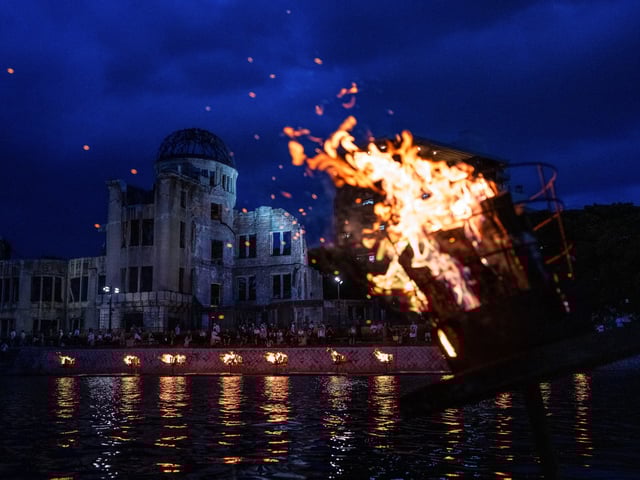 Bonfires are lit along the Motoyasu River in front of the Atomic Bomb Dome during a remembrance ceremony in Hiroshima, Tuesday, Aug. 5, 2025 on the eve of the 80th anniversary of the atomic bombing. (AP Photo/Louise Delmotte)