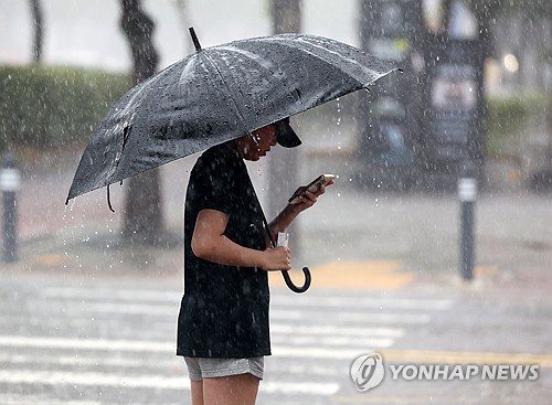 A person waits for a crosswalk signal in Gwangju, about 270 kilometers south of Seoul, under heavy rainfall on July 17, 2025. (Yonhap)