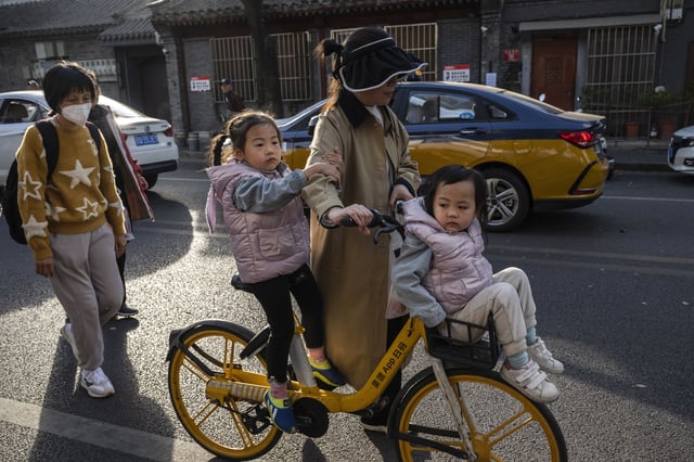 A women pushes her children on a shared bike near the Shichahai Lake and Houhai Lake areas on November 3, 2023 in Beijing, China.