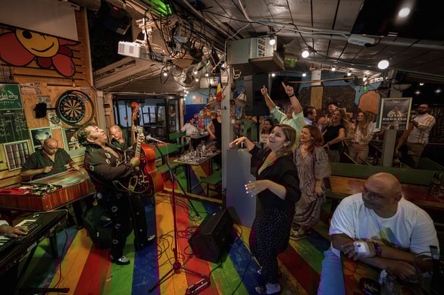 Customers dance as Tudor Lakatos, who goes by the stage name Elvis Rromano, performs at the Terasa Florilor restaurant with the Taraful Frunzelor band, in Bucharest, Romania, Friday, June 20, 2025. (AP Photo/Andreea Alexandru)