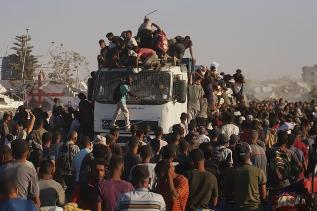 Palestinos montan en un camión cargado de alimentos y ayuda humanitaria mientras avanza por el corredor de Morag, en el sur de la Franja de Gaza.