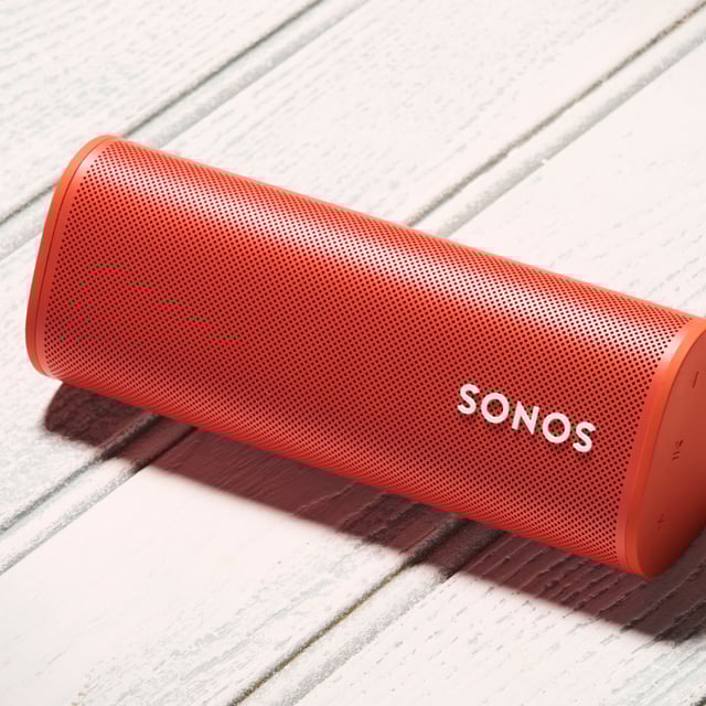Close up of a red wireless portable Sonos Roam Bluetooth speaker on white background.