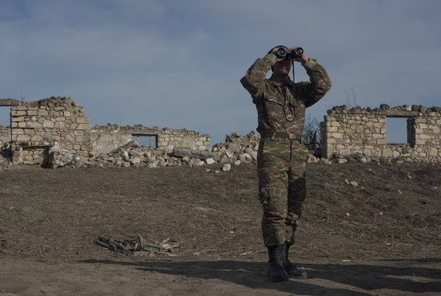 An ethnic Armenian soldier looks through binoculars as he stands at fighting positions near the village of Taghavard in the region of Nagorno-Karabakh, January 11, 2021. Picture taken January 11, 2021. REUTERS/Artem Mikryukov/File Photo