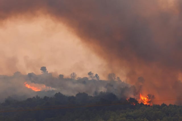 Les arbres brûlent lors d’un incendie de forêt au lever du soleil près de Saint-Laurent-de-la-Cabrerisse, près de Narbonne, dans le sud de la France, le 6 août 2025.