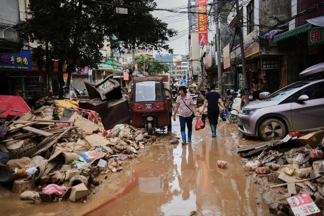 ARCHIVO - En esta imagen, distribuida por la agencia noticiosa estatal Xinhua, residentes cruzan una calle anegada llena de escombros tras el desbordamiento de un río después de días de intensas precipitaciones, en el condado de Huaiji, en la provincia de Guangdong, en el sur de China, el 19 de junio de 2025. (Deng Hua/Xinhua vía AP, archivo)