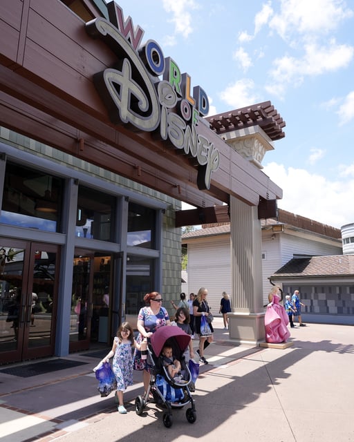 Tourists stroll by the World of Disney store at Disney Springs shopping and entertainment district Tuesday, Aug. 5, 2025, in Lake Buena Vista, Fla. (AP Photo/John Raoux)