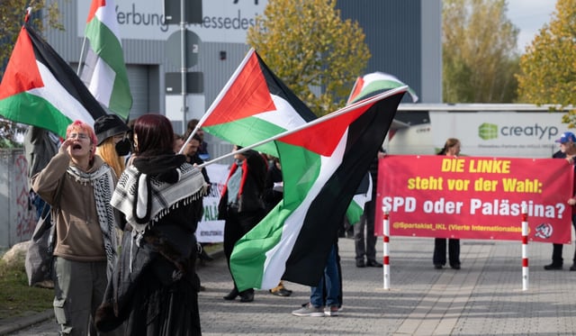Palästina-Flaggen wehen auf einer propalästinensischen Kundgebung auf dem Messegelände, wo der Bundesparteitag der Partei Die Linke stattfindet. Auf einem Transparent steht «Die Linke steht vor der Wahl: SPD oder Palästina?»