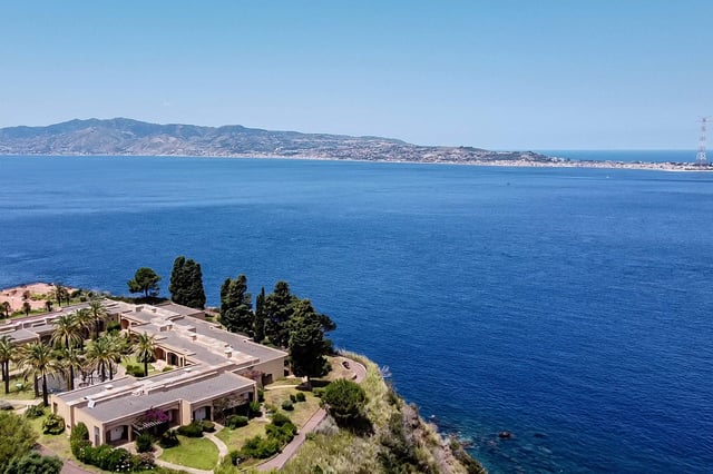 (FILES) A general aerial view shows the Sicilian coast towards Cape Torre Faro, over the Strait of Messina, taken from the outskirts of the town of Scilla, in Calabria region in southern Italy, on July 7, 2020. Italy&#39;s government on August 6, 2025 approved a 13.5-billion-euro ($15.6-billion) project to build the world&#39;s longest suspension bridge connecting the island of Sicily to the mainland. (Photo by Andreas SOLARO / AFP)