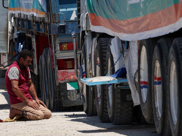 A truck driver prays as trucks carrying humanitarian aid line up near the Rafah border crossing between Egypt and the Gaza Strip, in Rafah, Egypt, August 6, 2025. REUTERS/Amr Abdallah Dalsh