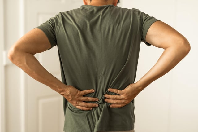 Man from behind with hands on lower back pain.