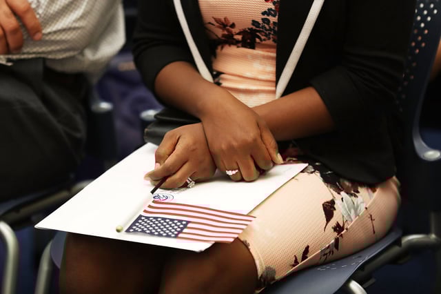 A person holds an American flag as they participate in a ceremony to become an American citizen during a U.S. Citizenship & Immigration Services naturalization ceremony at the Miami Field Office on August 17, 2018 in Miami, Florida.