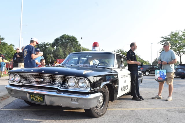 Retired Orland Park police Officer Michael Dalaly stands next to his restored 1963 Ford police car and chats with residents Tuesday, Aug. 5 during National Night Out at the Public Safety Complex in Orland Park. (Jesse Wright/Daily Southtown)