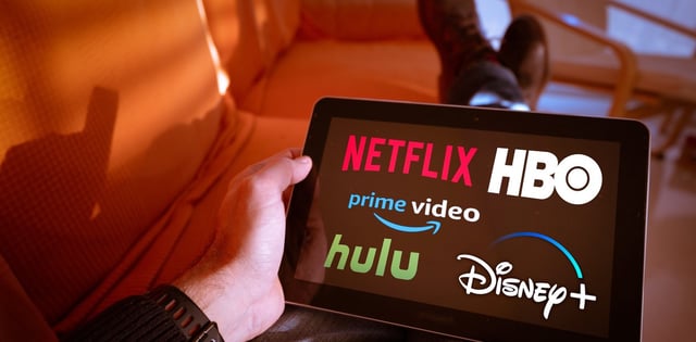 Un hombre sostiene una tableta con los logotipos de Netflix hulu, amazon video, HBO y Disney + en la pantalla. Foto Shutterstock