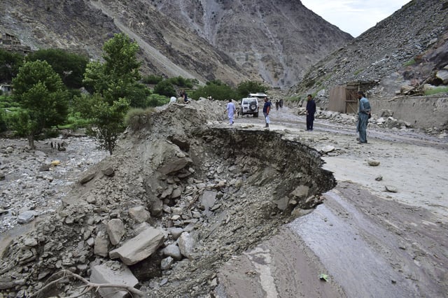 FILE - Local residents walk on a damaged road following a cloudburst triggered landslide and flash flood on a highway near the Chilas district, northern Pakistan, July 23, 2025. (AP Photo/Saqib Manzoor, File)