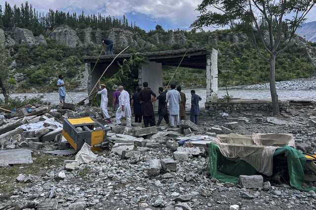 Local residents collect useful items through the rubble of their houses, which were damaged by July 22 floods, at the bank of Hunza River in Sarwarabad, a town in the northern Pakistan, Wednesday, Aug. 6, 2025. (AP Photo/Abdul Rehman)