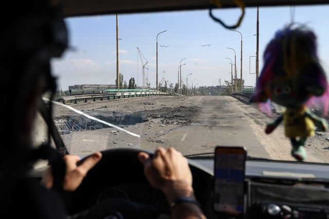A car with volunteers drives over a damaged bridge after Russian air bomb attacks in Kherson, Ukraine on August 4.