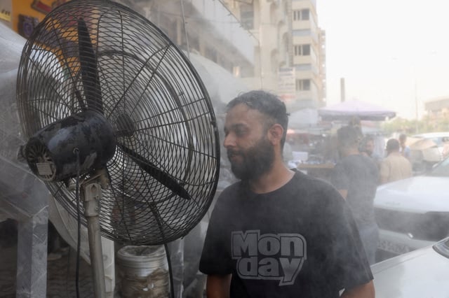 A man cools his face with water mist from sprinklers during a heatwave in Baghdad, Iraq. REUTERS/Ahmed Saad/File Photo