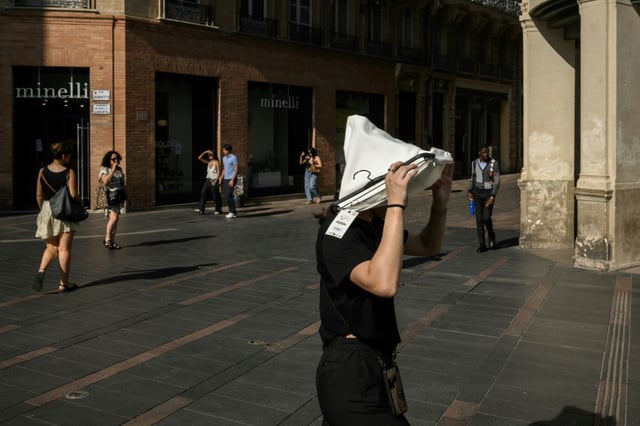 Une femme se protège du soleil avec un vêtement le 1er juillet 2025 à Toulouse lors d'une vague de chaleur