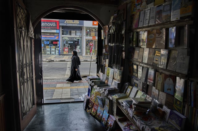 A Kashmir woman walks past a book store in Srinagar, Indian controlled Kashmir, Thursday, Aug. 7, 2025. (AP Photo/ Dar Yasin )
