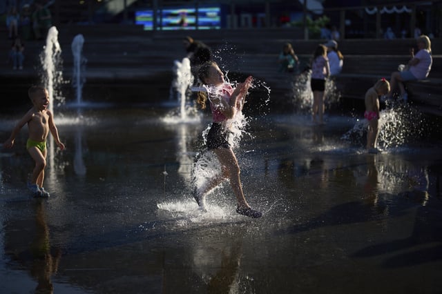 FILE - Children cool off in a fountain at VDNKh (The Exhibition of Achievements of National Economy) enjoying the warm weather during sunset in Moscow, Friday, July 25, 2025. (AP Photo/Alexander Zemlianichenko, File)
