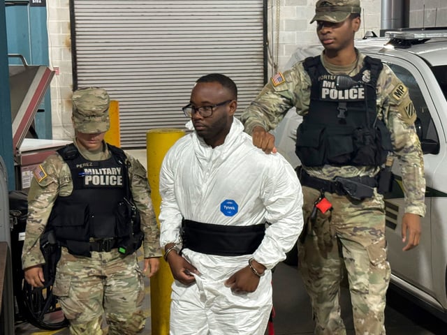 Sgt. Quornelius Radford, a suspect in the shooting of five soldiers at Fort Stewart, is escorted by military police into a booking room at the Liberty County Jail in Hinesville, Ga., Wednesday, Aug. 6, 2025. (AP Photo/Lewis M. Levine)