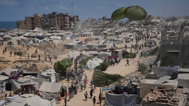 Palestinians rush to collect humanitarian aid airdropped by parachutes into Gaza City, northern Gaza Strip.