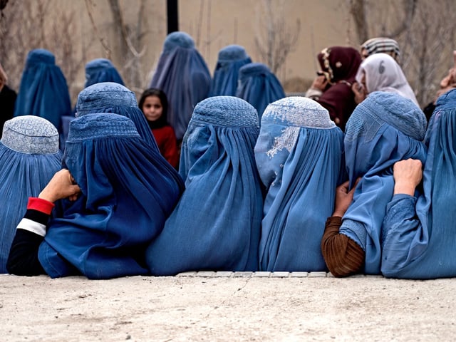 Afghan burqa-clad women wait in a queue to receive free iftar meal during the Islamic holy fasting month of Ramadan, on the outskirts of Kabul on March 12, 2025. (Photo by Wakil KOHSAR / AFP)