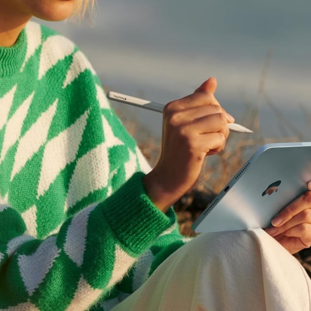 woman sitting outside using Apple iPad Mini