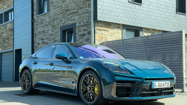A blue Porsche Panamera Turbo S next to a farmhouse