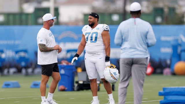 Los Angeles Chargers offensive tackle Rashawn Slater (70) talks to a coach on the field during an NFL training camp Monday